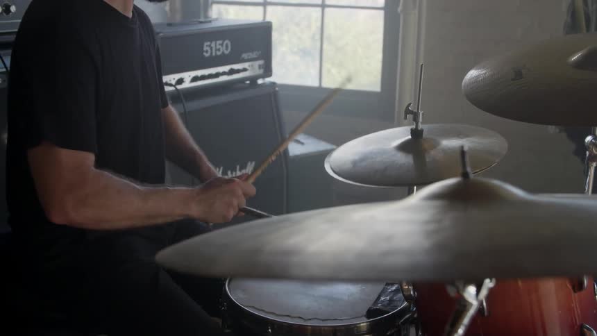 Man plays the drums and hits the cymbals with drumsticks