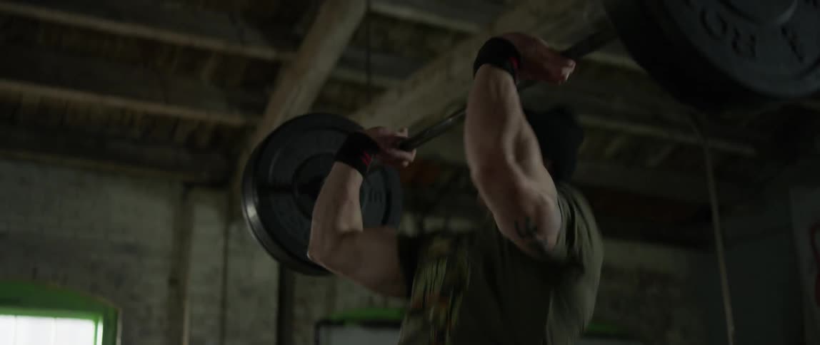 A man is deadlifting weights in a gym during the day