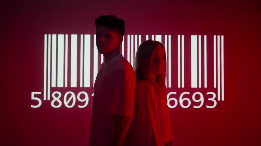 Girl and boy stand in front of screen with a barcode