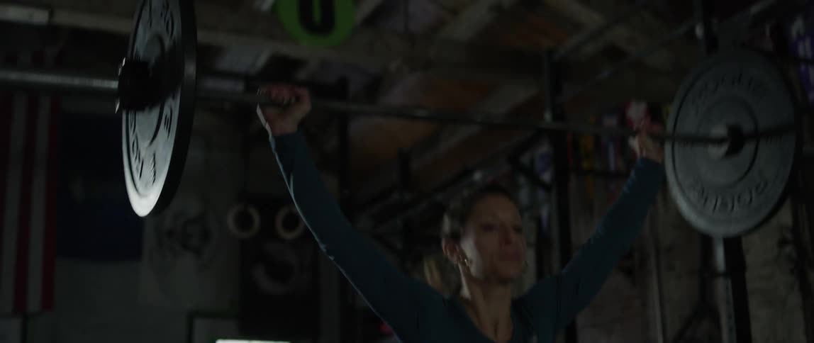 A woman is deadlifting weights in a gym during the day