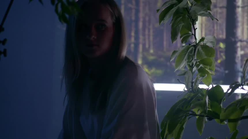 A woman stands in front of a forest projection on the wall