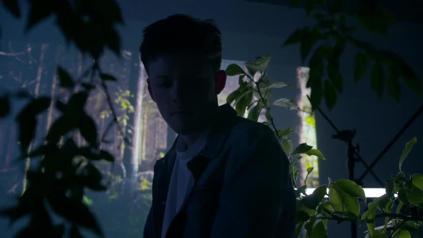 A man sits in a room full of plants