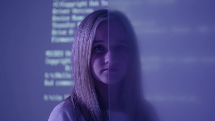 A woman stands in front of frosted glass as a projection is shown on the wall