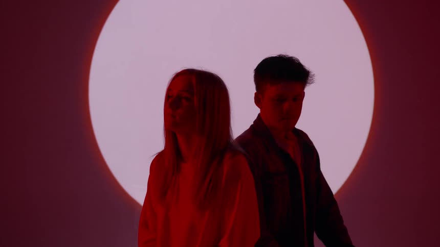 A couple sits in front of a white circle