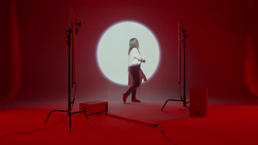 Young woman stands in front of a large white circle
