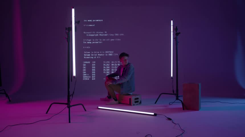 A man sits in front of an abstract projection