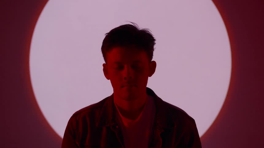 A man sits in front of a red spotlight