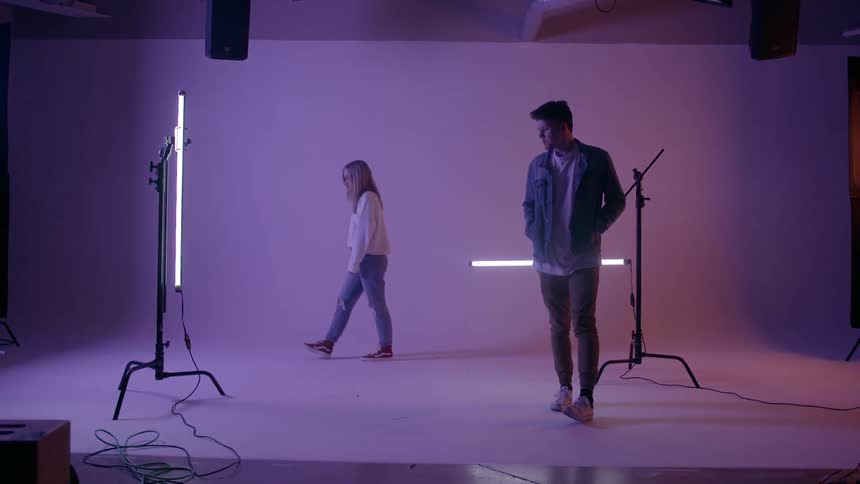 A man and woman are milling about in a room with lights