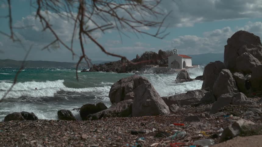 Wide landscape view of a rocky shoreline with a small church off in the background