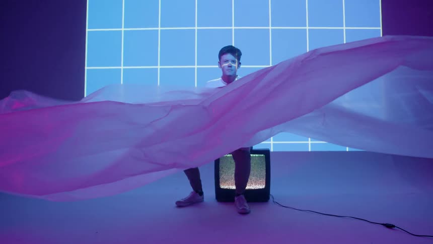 Cloth flutters in front of a man sitting on a tv