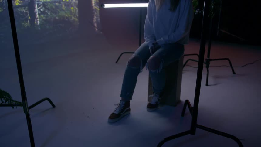 Woman sits on a wooden block as she slightly moves her foot