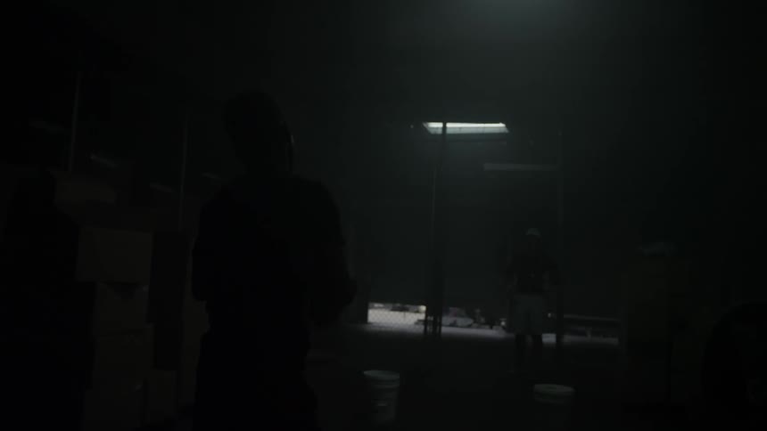 Two men toss a football in a dark building