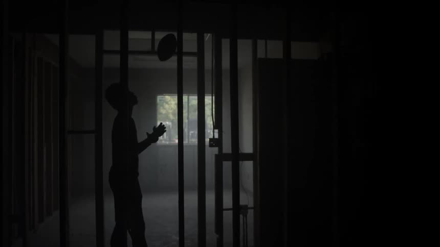 A man stands in an unfinished doorway tossing a football