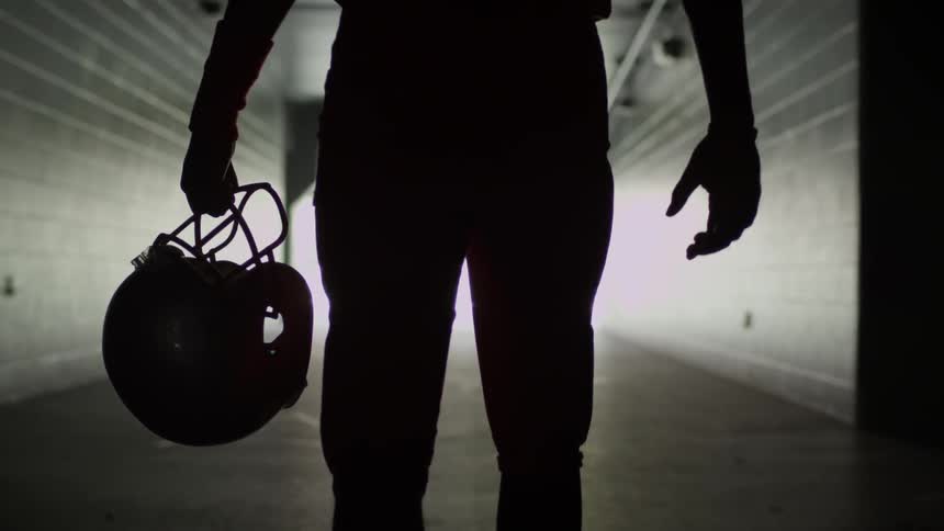 Man carries a helmet as he walks down a corridor