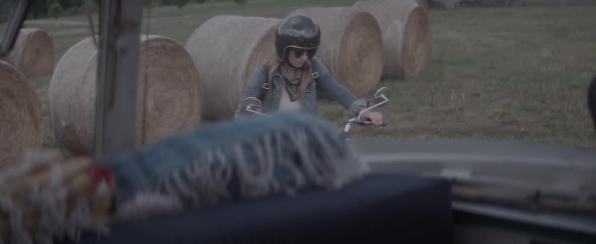 Woman rides a motorcycle then gets off and removes her helmet