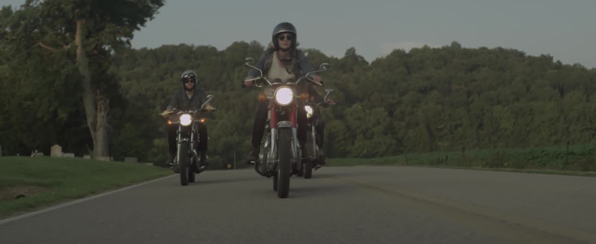 A woman and her friends ride motorcycles on a road