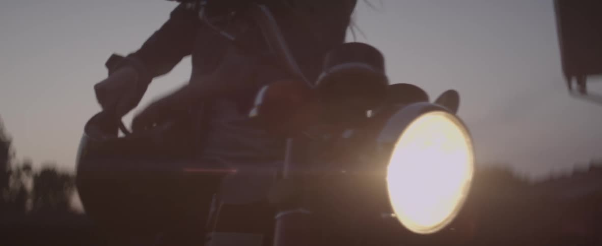 Woman puts a helmet on and while standing next to a motorcycle