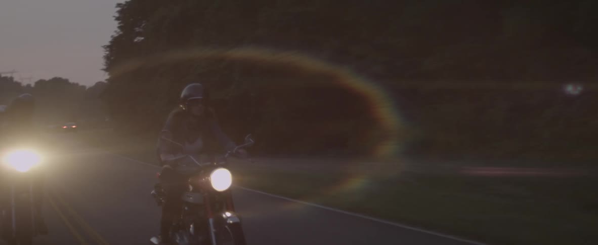 A woman is riding a motorcycle on a rural road