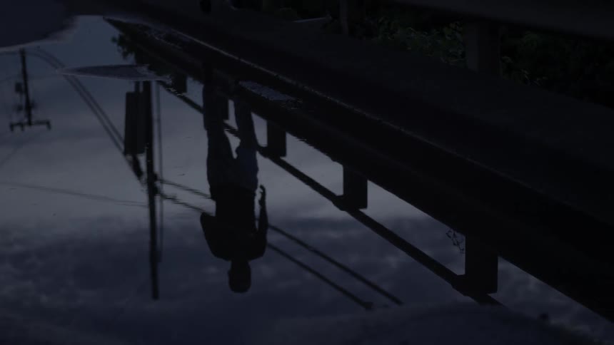 A man is jogging on a path next to a puddle at dusk