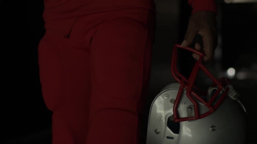 A football player carries his helmet as he walks