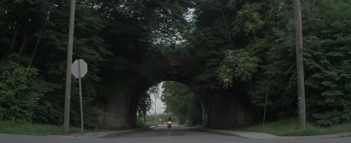 A woman rides a motorcycle through an open tunnel