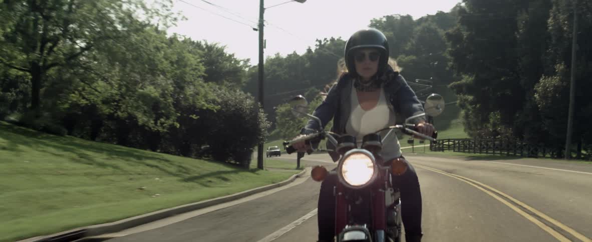 A woman rides a motorcycle down the road