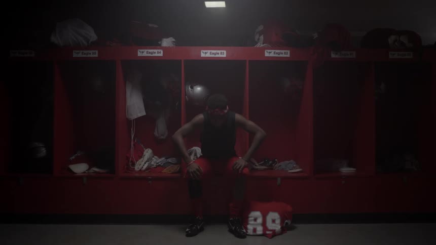 Man walks through a dimly lit locker room and sits down