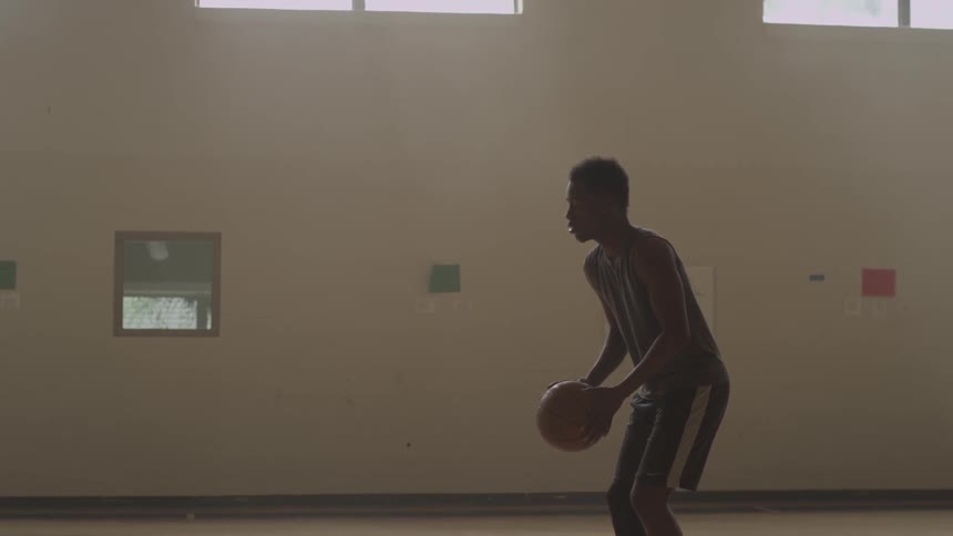 A boy bounces a basketball before taking a shot