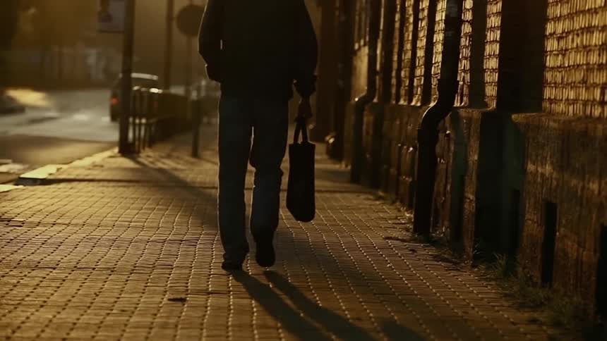 A man carrying a bag is walking down the street