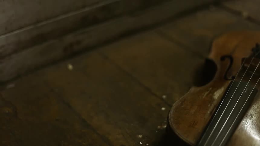 A violin sits on the floor as light flashes on it