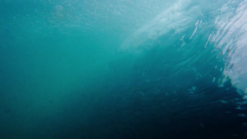 Crashing waves stir up debris and bubbles beneath the ocean