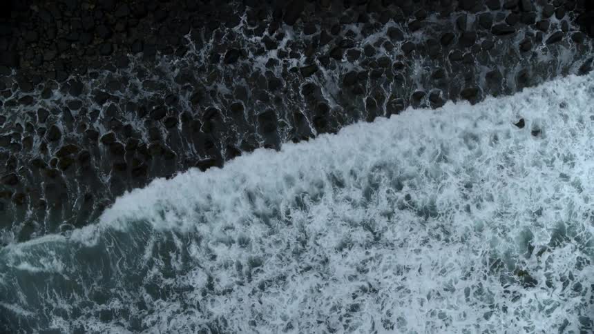 Waves are rolling onto a rocky beach during the day