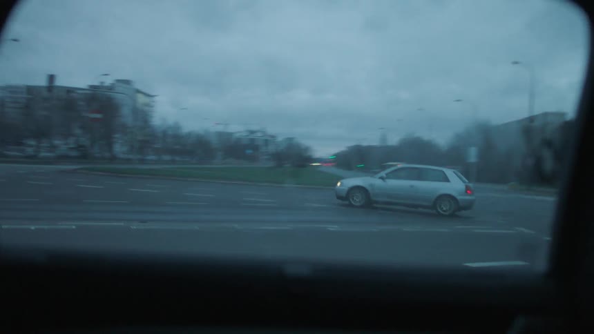 A vehicle navigates a series of urban streets at dusk on a cloudy day