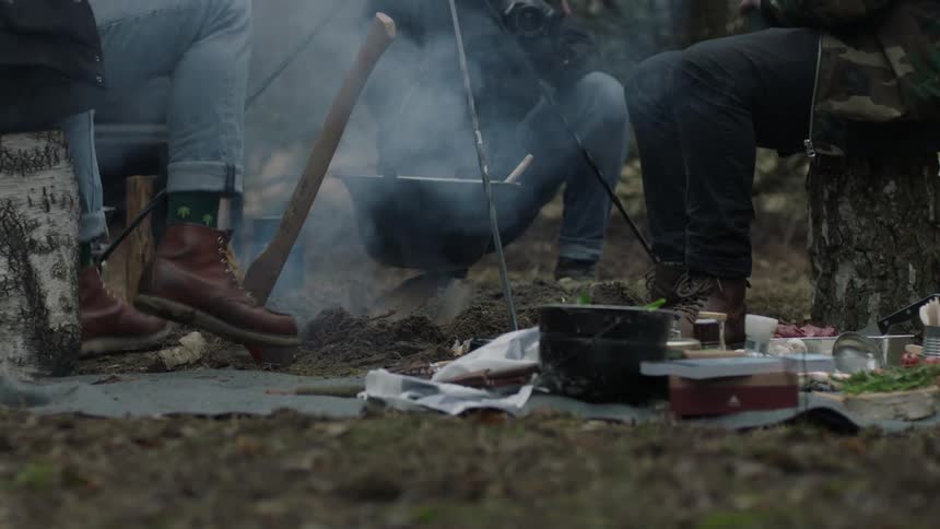 Men sitting next to a pot over an open fire