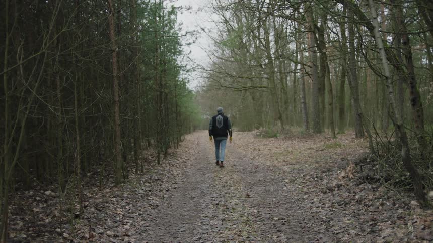 Man walks on a leafy trail through the woods