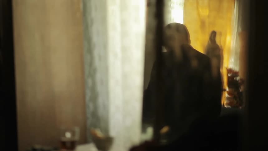 An older man stands in a room and talks