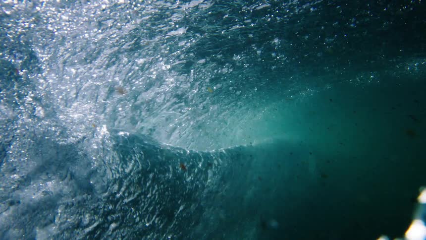 The ocean tide and waves crash creating bubbles beneath the surface