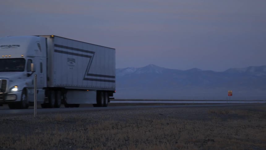 A big rig transport truck travels down the road