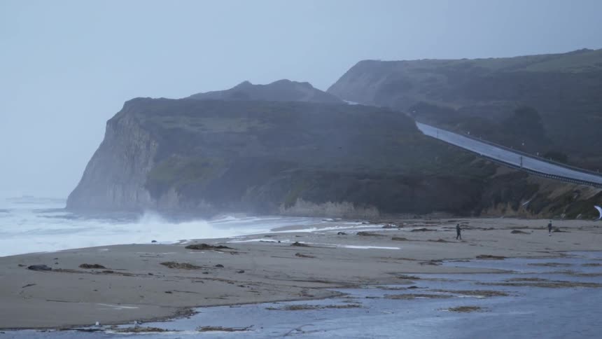People fly a kit on a beach on a hazy day