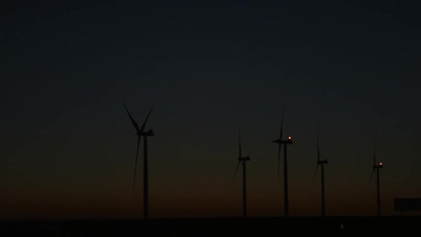 Wind turbines spin outside at dusk