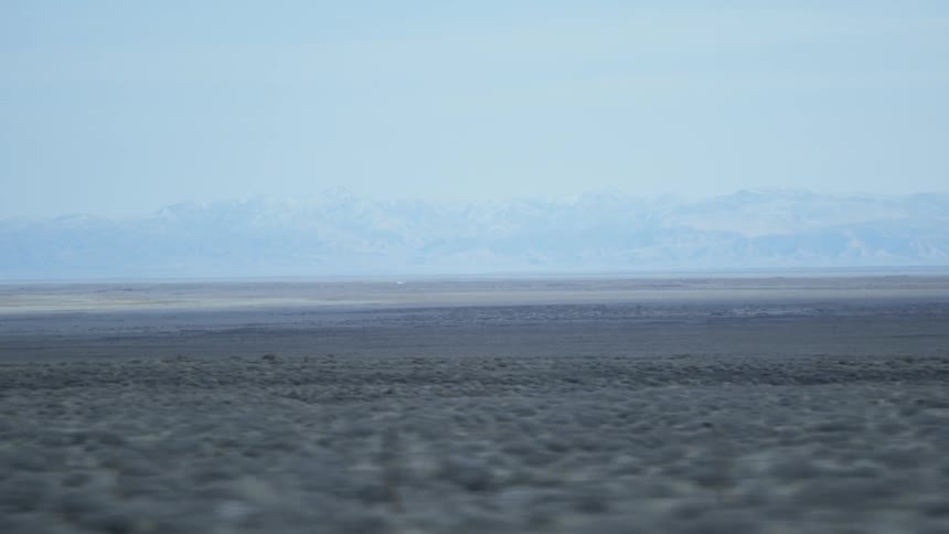 Mountains sit under a blue sky next to a large field
