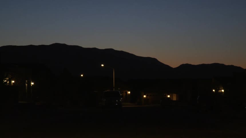 An suv is parked in front of a street light in a neighborhood at night