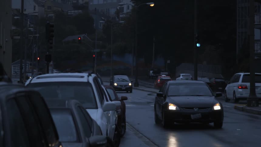 Traffic drives on a neighborhood street on a wet evening
