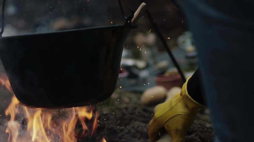 Man cooks over an outdoor fire