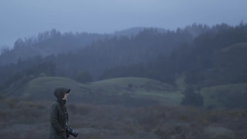 A photographer walks outside in the rain