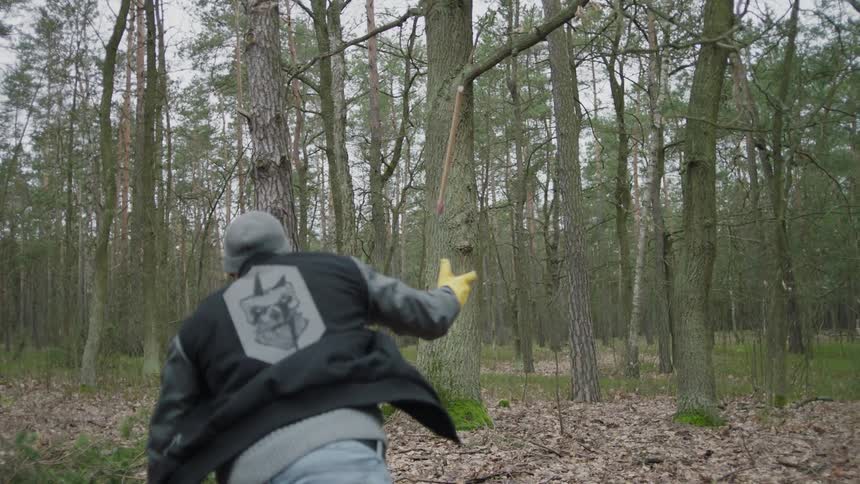 Man throws an ax into the trunk of a tree