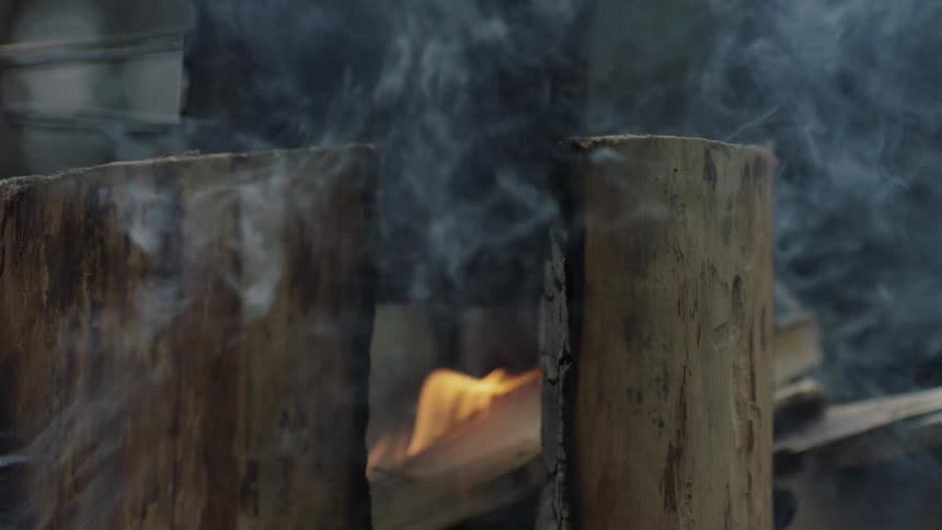 Smoke from a campfire curls around a cup