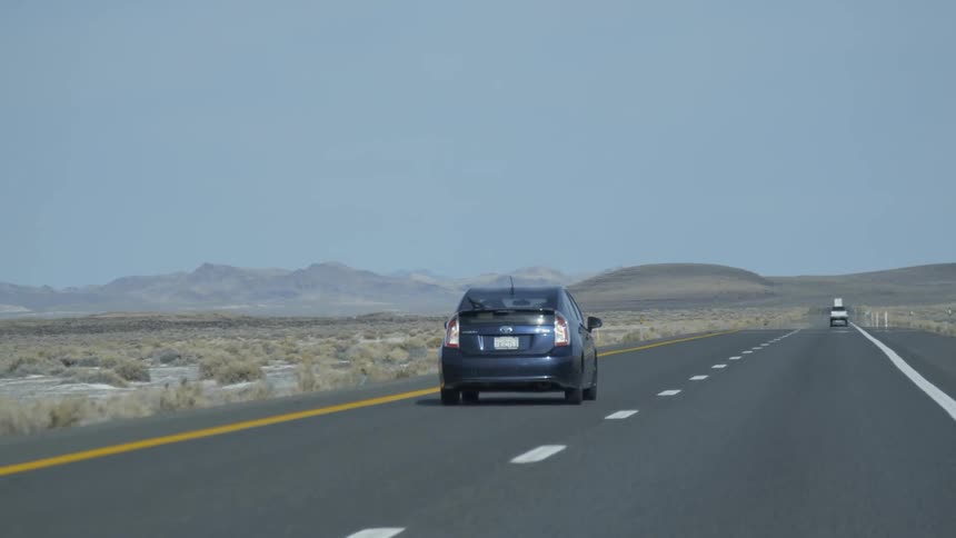 Vehicles travel on a desert highway on a sunny day