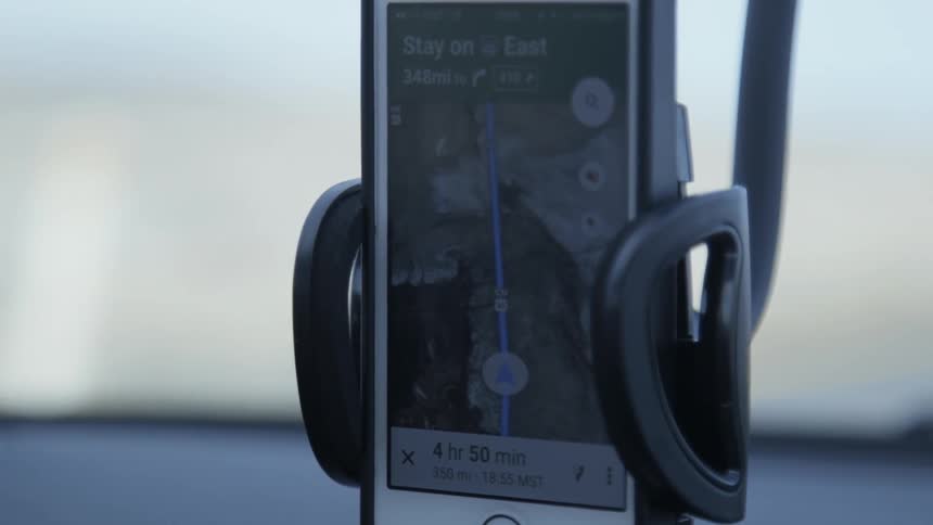 A cell phone positioned on a vehicle's dashboard is mapping a route