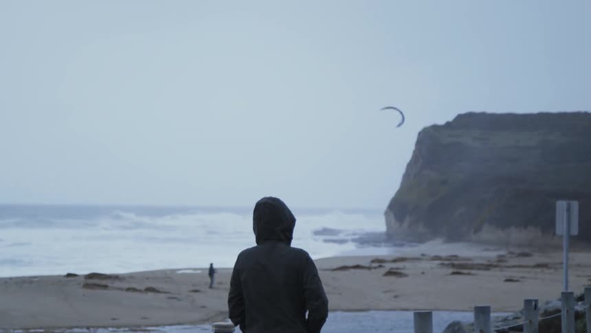 A woman is walking on a beach on a cold day